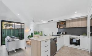 a kitchen with white cabinets and a table and a chair at Gemstone in Morayfield