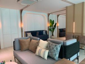 a living room with a couch and two mirrors at The Title Serenity Naiyang in Ban Bo Han