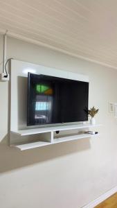 a flat screen tv on a white wall at Quarto Privativo Próximo à BR in São José +4 photos