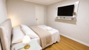 a white bedroom with a bed and a tv at Quarto Privativo Próximo à BR in São José