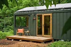 a green tiny house with a wooden deck and a chair at awake Gojome in Akita