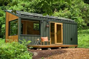 a green tiny house with a chair in a yard at awake Gojome in Akita