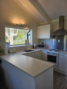 a kitchen with white appliances and a large window at Rolling Hills Cottage in Tauwhare