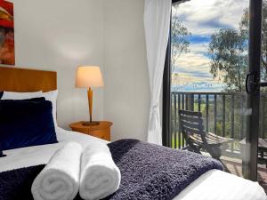a bedroom with a bed and a window with a balcony at Vilamoura in Pokolbin