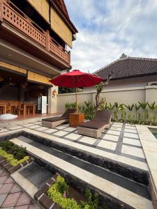 a patio with a red umbrella and chairs and a table at Umah Nayoye Amed in Ambat