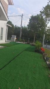 a yard with green grass in front of a house at Cahaya 382 in Sitiawan