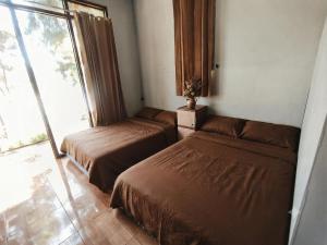 two beds sitting in a room with a window at Hajeka Family 1 in Palayangan +1 photo