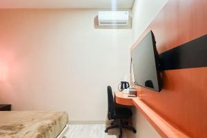 a bedroom with a desk with a tv on a wall at Urbanview Hotel Get Inn Pollux Batam in Batam Center