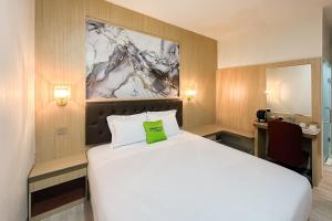 a bedroom with a white bed with a green pillow on it at Urbanview Hotel Get Inn Pollux Batam in Batam Center