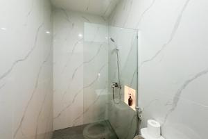 a bathroom with a glass shower with a toilet at Urbanview Hotel Get Inn Pollux Batam in Batam Center