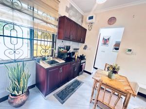 a kitchen with wooden cabinets and a sink and a table at Easyhomes bungalow apartment in Dar es Salaam