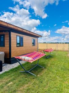 two picnic tables in the grass in front of a cabin at Fajny domek Wójcice in Otmuchów