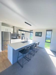 a kitchen with a blue island in a room with chairs at Springhill at The Beach in Karikari Peninsula