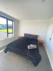 a bedroom with a bed and a large window at Springhill at The Beach in Karikari Peninsula