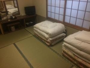 a room with two stacks of mattresses on the floor at Ryokan Meiryu in Nagoya