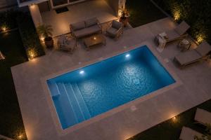 an overhead view of a pool with chairs and a table at Sea Breeze & Nature villa, with heated pool and garden retreat in Kremasti