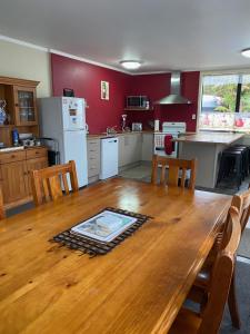 a kitchen with a wooden table with chairs and a kitchen with a refrigerator at Arthurstown Rd Riverview House in Ruatapu