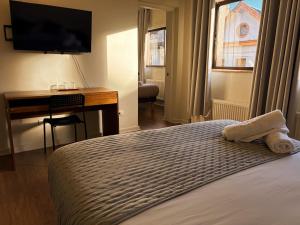 ein Schlafzimmer mit Bett, Schreibtisch und Fernseher in der Unterkunft Budget Hotel Central in Osorno