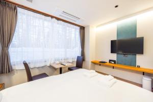 a hotel room with two beds and a flat screen tv at WHITE HOTEL GRAND HAKUBA in Omachi
