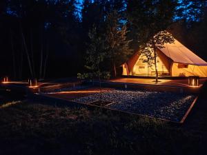a tent at night with lights in the grass at AVOTUPJI GLEMPING telts in Allaži