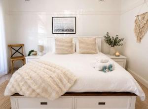 a bedroom with a white bed with a teddy bear on it at Cozy Loft Beach House in Wollongong