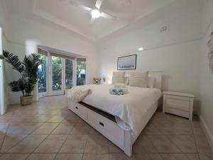 a bedroom with a large white bed with a ceiling fan at Cozy Loft Beach House in Wollongong +48 photos