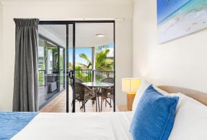 a bedroom with a bed and a balcony with a table at Belaire Place Motel Apartments in Caloundra +64 photos