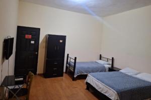 a bedroom with two beds and a dresser and a tv at OYO Seoul Garden Apodaca in Monterrey