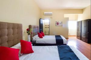 two beds in a hotel room with red pillows at OYO Seoul Garden Apodaca in Monterrey