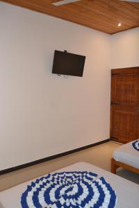 a bedroom with a bed and a flat screen tv on the wall at Nilaveli Shan Guest in Trincomalee