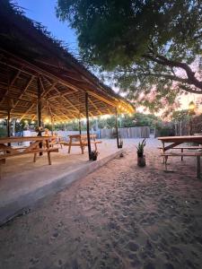 a picnic shelter with picnic tables on the beach at Kora Beach House & Restaurant Cafe in Ampara