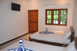 a room with two beds and a tv and a window at Nilaveli Shan Guest in Trincomalee +35 photos