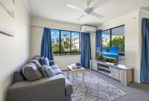 a living room with a couch and a flat screen tv at Belaire Place Motel Apartments in Caloundra