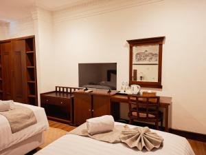 a room with two beds and a desk with a television at Hotel Butik Sawunggaling in Bandung
