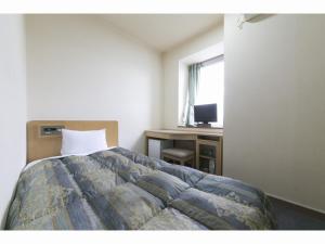 a bedroom with a bed and a desk and a window at Business Hotel Okada Toyohashi in Toyohashi