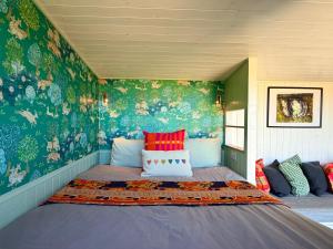 a bedroom with a large bed with colorful wallpaper at Tŷ Ni Tiny Houses in Bridell