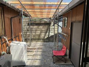 a room with a red chair and a building at ゲストハウスぬっく in Tanabe