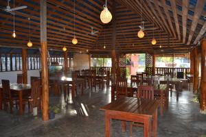 a restaurant with wooden tables and chairs and lights at Nilaveli Shan Guest in Trincomalee