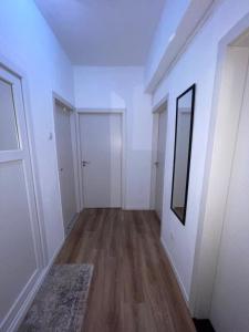 an empty hallway with white walls and wood floors at Bleon Apartment in Prizren