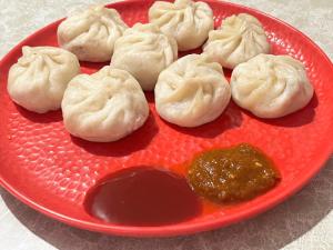 a red plate of dumplings with a dipping sauce at Riyang Homestay in Mirik
