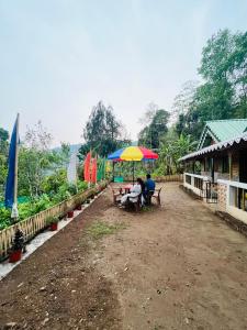 two people sitting at a table under a colorful umbrella at Riyang Homestay in Mirik