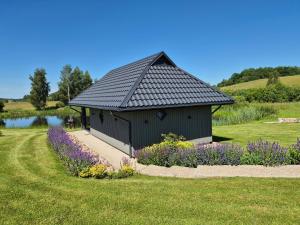 a black building in a field with purple flowers at Namelis 'Lizdas' Plateliuose in Plateliai