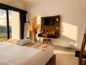 a bedroom with a bed with a television and a desk at Bukit Pinggan Kintamani in Baturaja