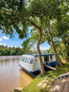 a boat parked next to two trees on a river at Vegas Nature Resort in Dankotuwa