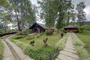 a garden with a barn and a path to a house at Kampoeng Regang By BHATARA in Patengan