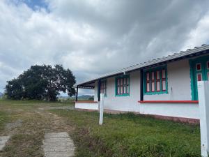 a white building with red windows on a field at Masinga FarmHouse in Filandia