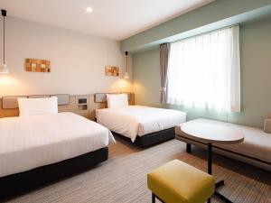 a hotel room with two beds and a window at Comfort Hotel Chitose in Chitose