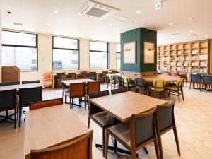 a library with tables and chairs and bookshelves at Comfort Hotel Chitose in Chitose