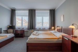 a hotel room with two beds and a desk and a desk at Hotel Morava Jevíčko in Jevíčko