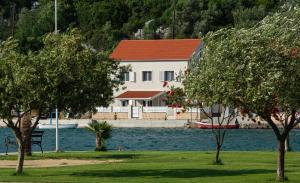 a white house with a red roof next to the water at First Line Seafront Luxury Apartman Kata in Rogotin